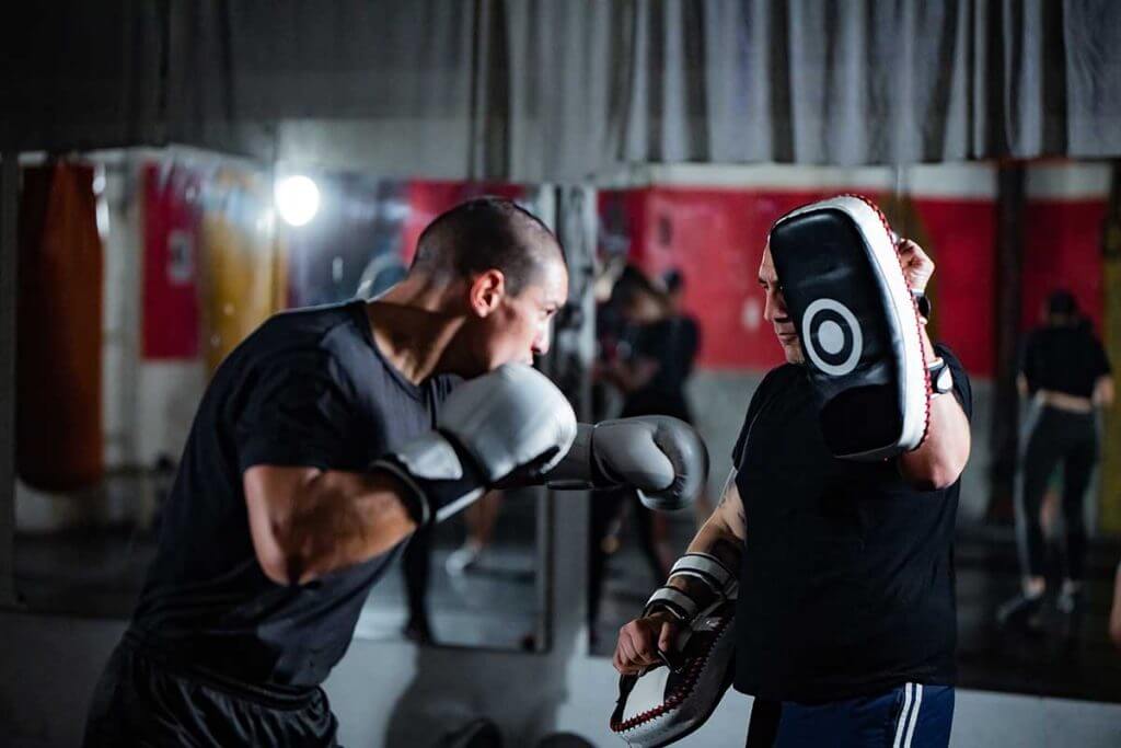 Adult man boxing with a trainer
