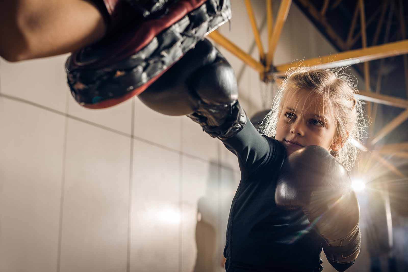 Young girl boxing with a trainer in a martial arts class