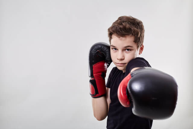 Young boy throwing punch in kids beginner kickboxing classes