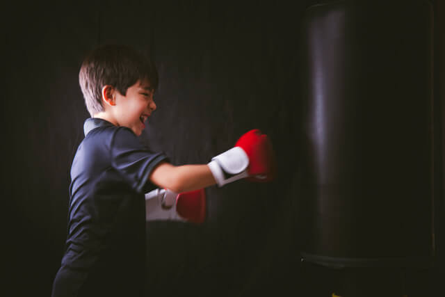 Young male throwing punch in kids beginner kickboxing classes